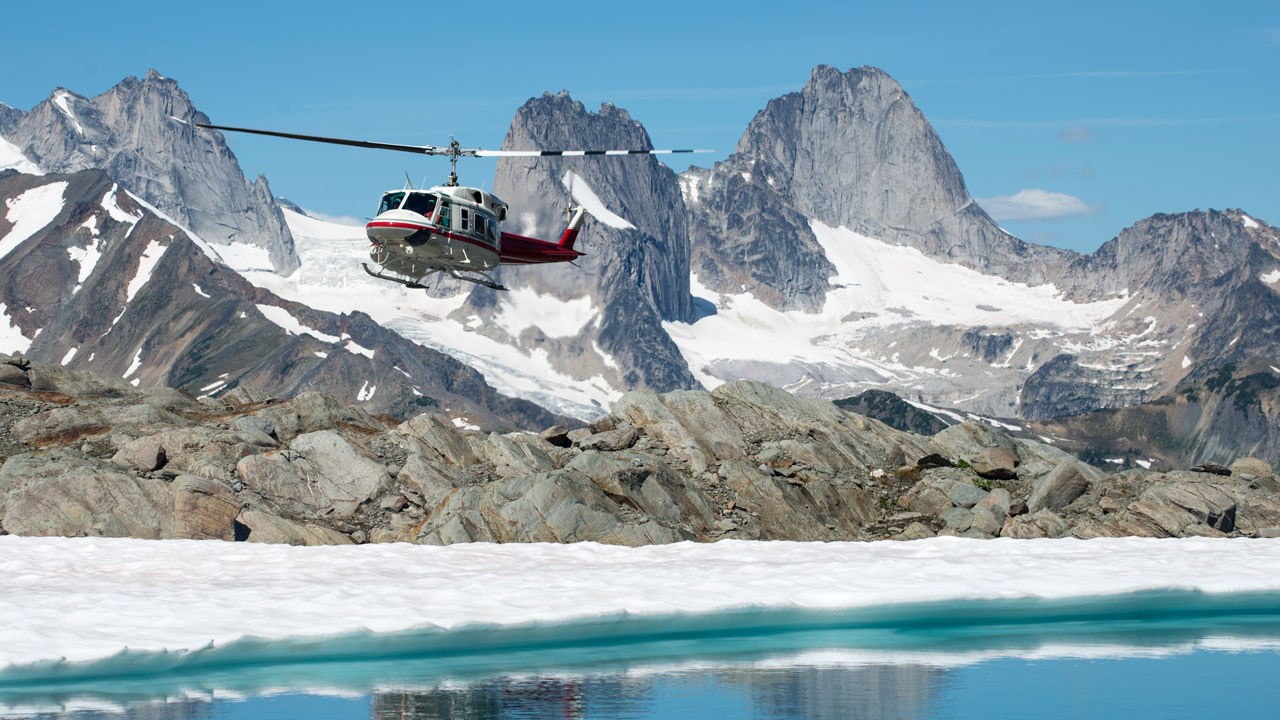 Helicopter hovering over a glacial lake in the Bugaboos in the Canadian Rockies
