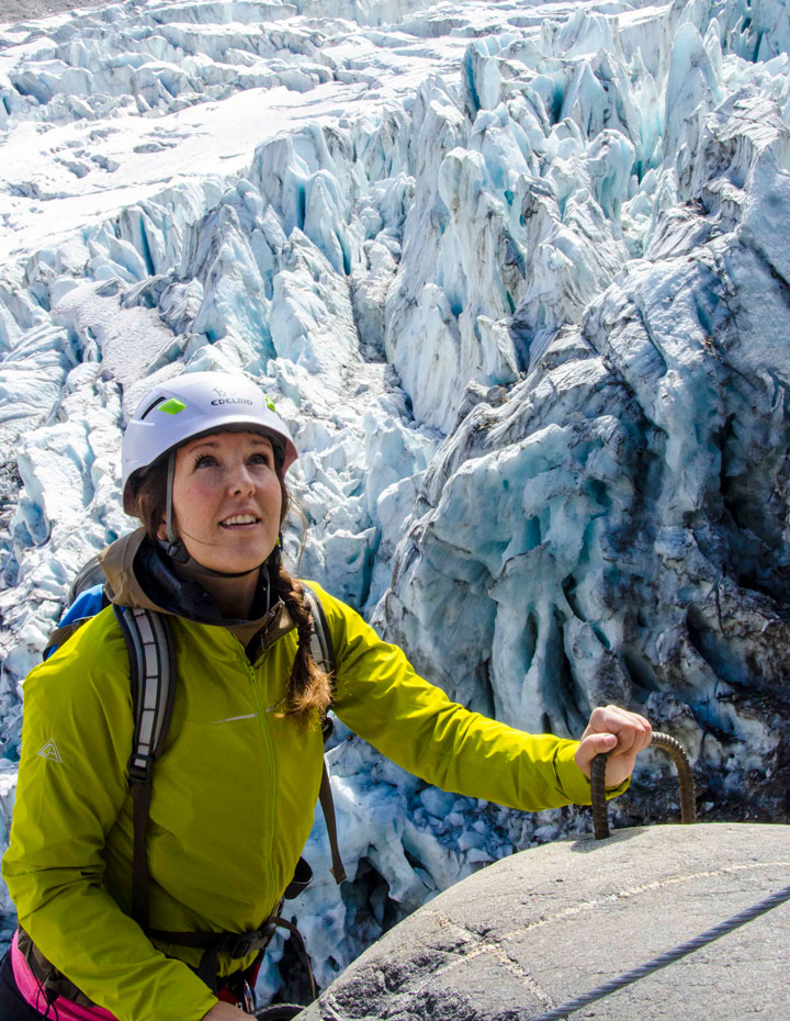 Woman climbing a Via Ferrata in front of Conrad Glacier in the Canadian Rockies